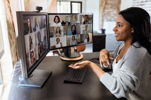 Woman gestures during virtual meeting with colleagues