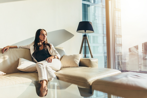 Young professional woman sitting on coach in high-end apartment.